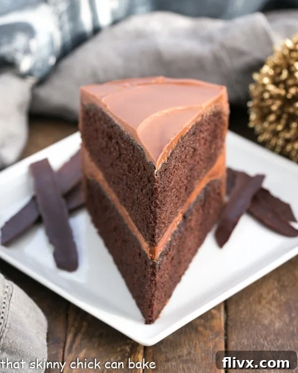 A slice of Chocolate Mayonnaise Cake resting on a square white plate, showing its rich, dark interior and creamy frosting.
