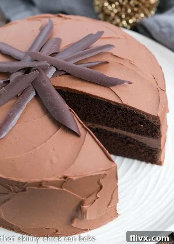 A completed Chocolate Mayonnaise Cake with a single slice removed, resting on a white serving plate.