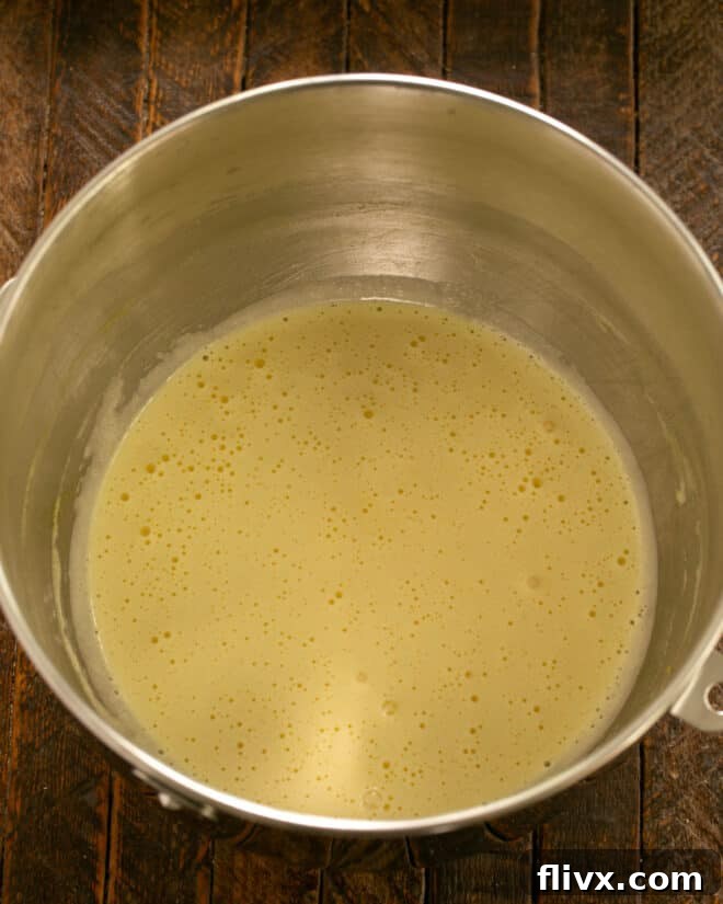 Eggs, sugar, and vanilla being beaten in a stand mixer, followed by mayonnaise.