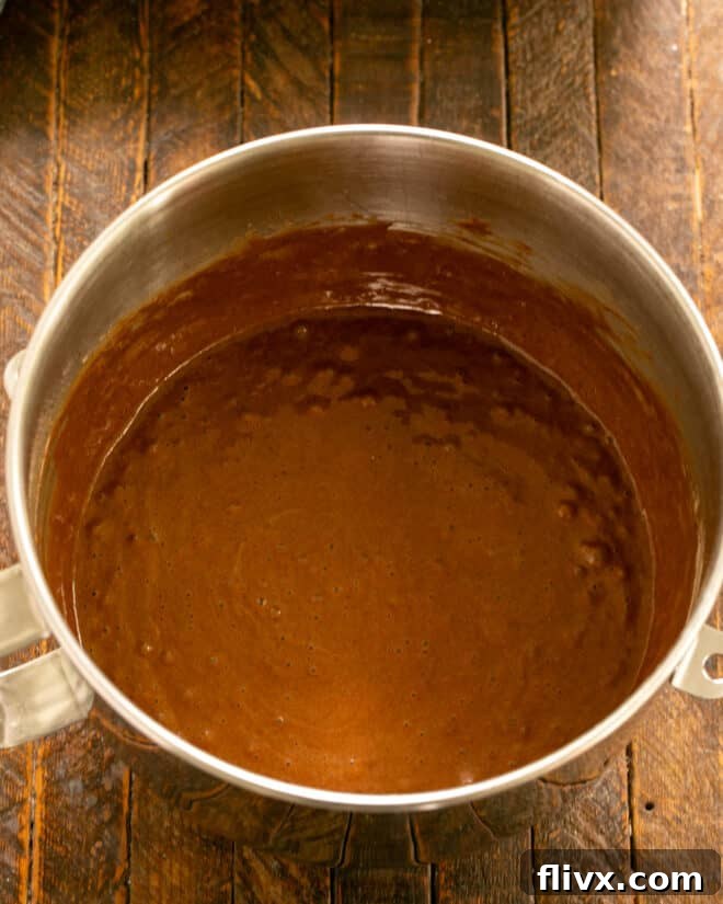 Scraping the sides of the mixing bowl to ensure all ingredients are incorporated.