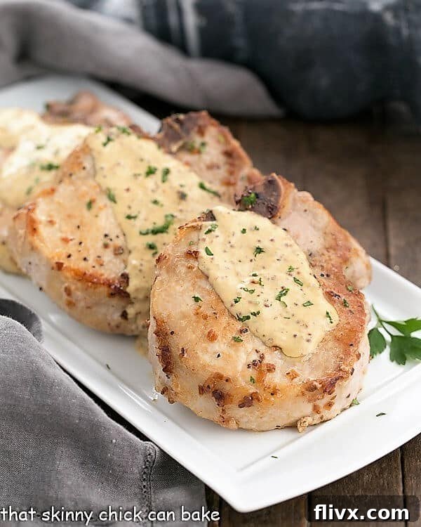 Pork Chops Dijonnaise artfully arranged on a rectangular serving tray, glistening with a generous drizzle of the creamy mustard sauce.
