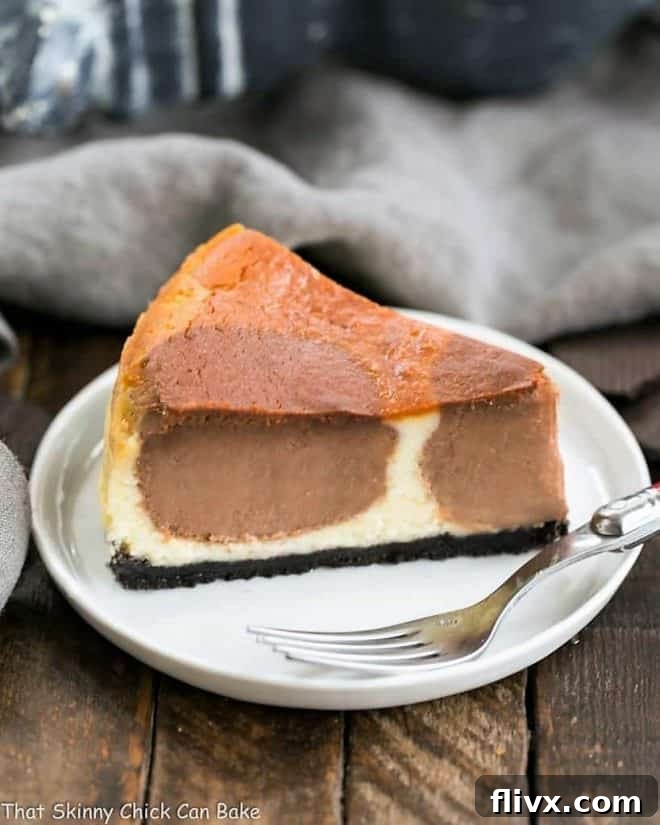 A slice of Polka Dot Cheesecake resting on a clean white dessert plate, with a fork poised to enjoy, emphasizing its inviting texture and signature chocolate dots.