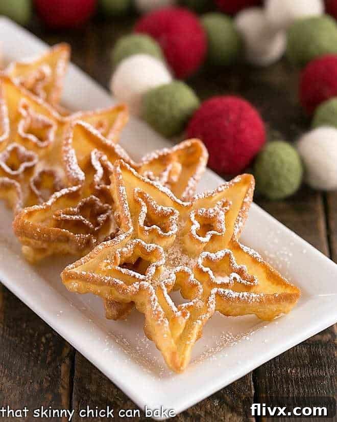 Delicate rosettes lined up on a narrow white tray, dusted with powdered sugar, ready for holiday festivities.