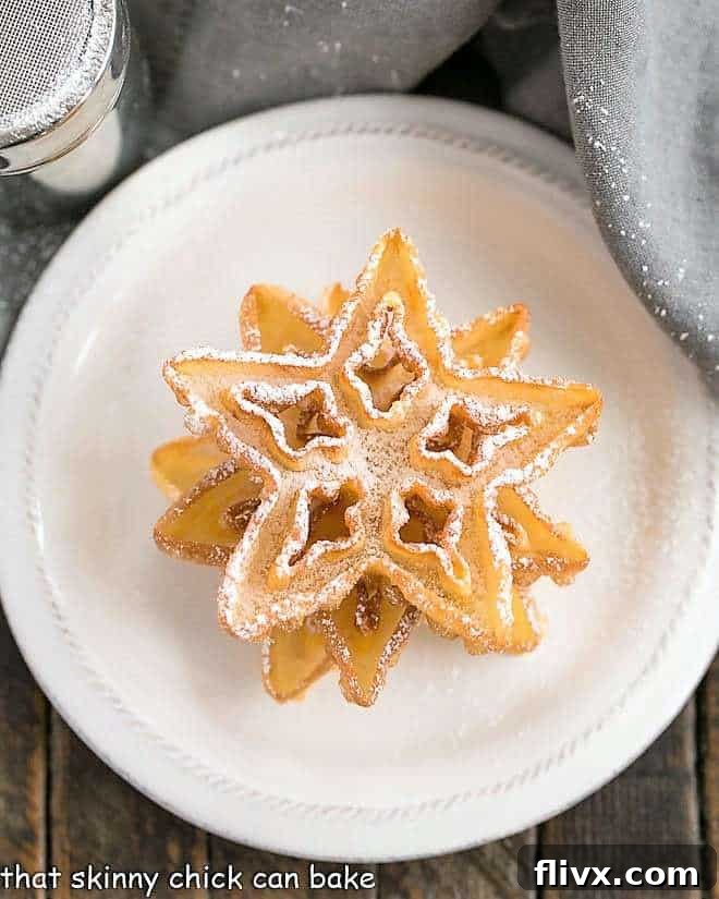 Three perfectly stacked, golden rosettes on a round plate, awaiting their powdered sugar dusting.