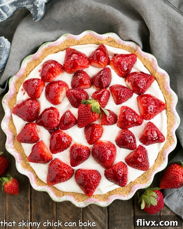 An overhead view of a beautifully arranged Strawberry Cream Pie, artfully topped with an abundance of fresh, glistening berries.