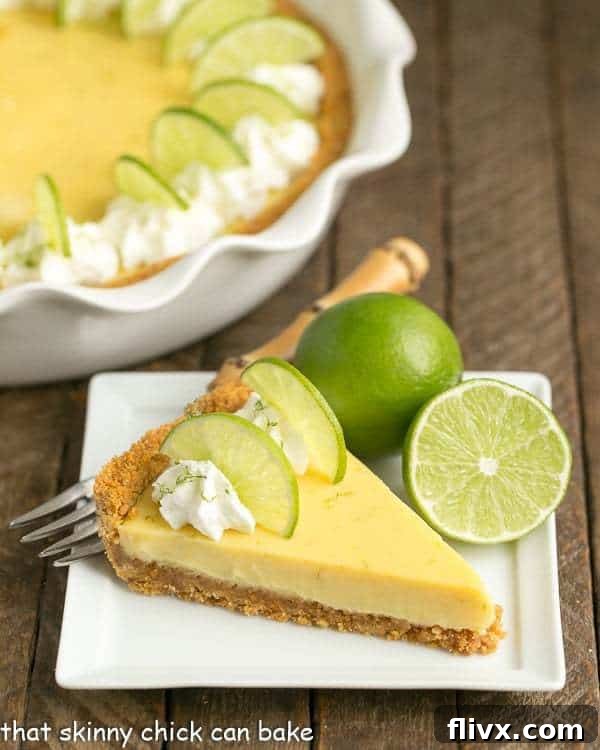 A perfectly sliced piece of Key Lime Pie with Graham Cracker Crust, garnished with whipped cream, on a square white dessert plate.