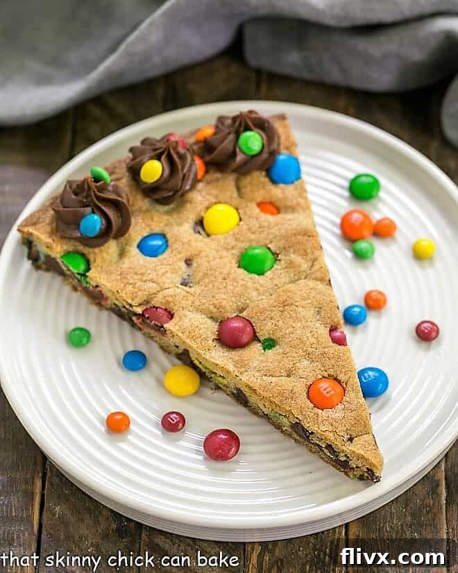 An inviting overhead shot captures the full glory of a large, freshly baked chocolate chip cookie cake, generously studded with colorful M&M's, filling the frame with warmth and delicious promise.