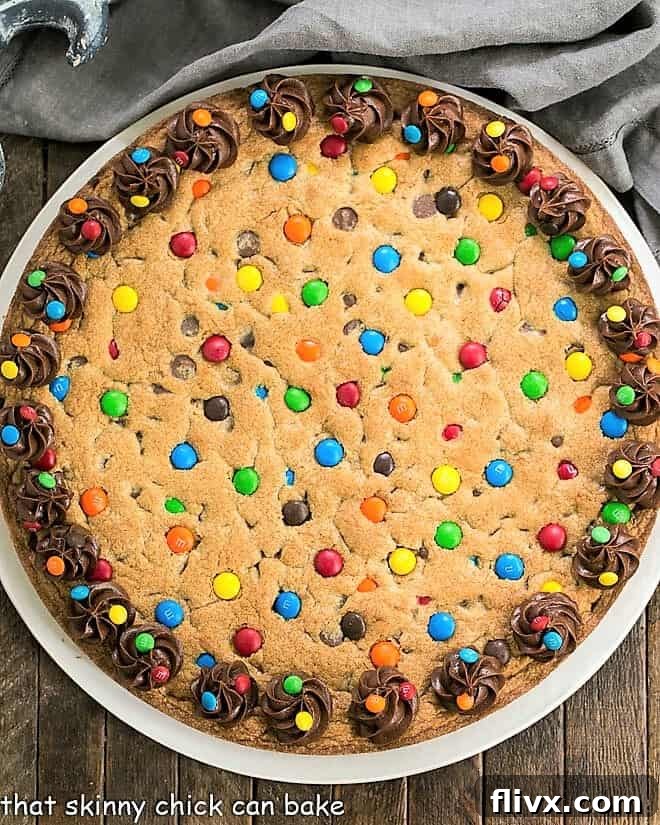 A top-down view of the beautifully decorated chocolate chip cookie cake, showcasing its perfect round shape and the artistry of the M&M arrangement, promising a sweet celebration.