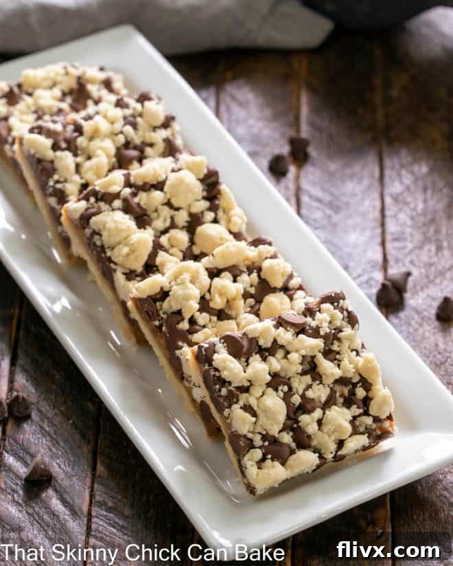 A close-up of several golden chocolate caramel bars with a crumbly streusel topping, arranged neatly on a white ceramic tray.
