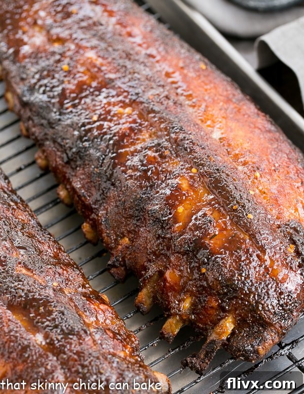 A full rack of Apricot Glazed Baby Back Ribs on a sheet pan after baking, glistening with glaze