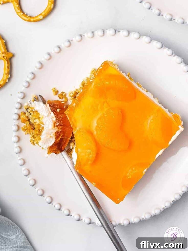 Mandarin orange Jello pretzel salad with layers of crunchy pretzel, creamy filling, and orange gelatin.