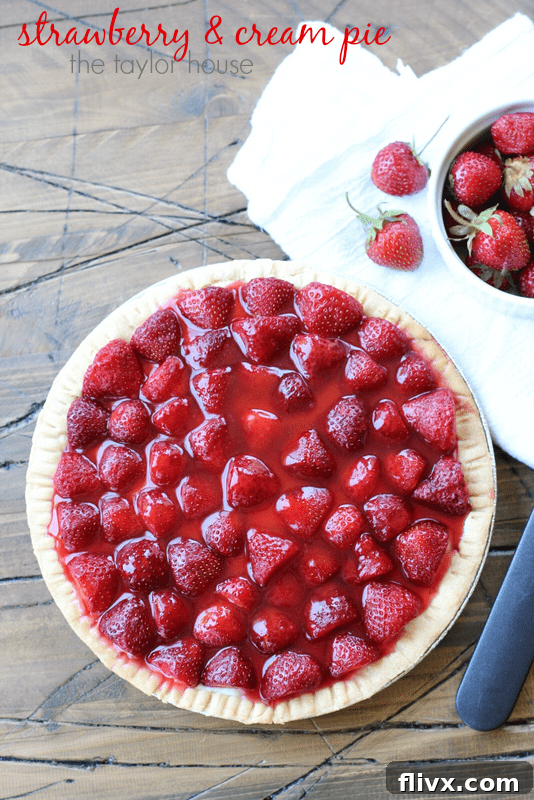 A slice of Summertime Strawberry Cream Pie with a flaky crust and fresh strawberries.