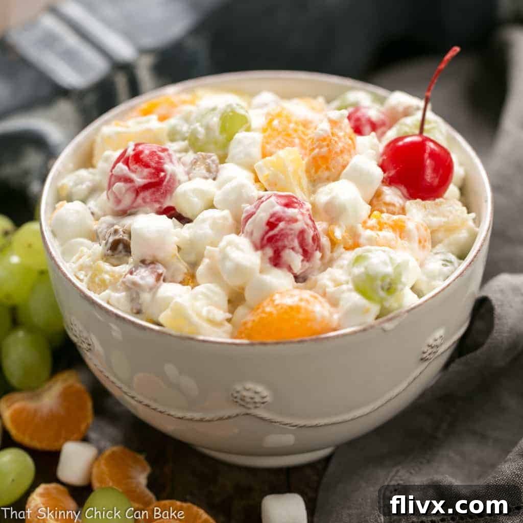 A bowl of the best ambrosia salad, brimming with fruit, marshmallows, and real whipped cream.
