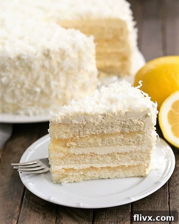 A perfectly sliced piece of Lemon Layer Cake revealing layers of moist cake, vibrant lemon curd, and fluffy Swiss Meringue Buttercream, served on a white dessert plate.