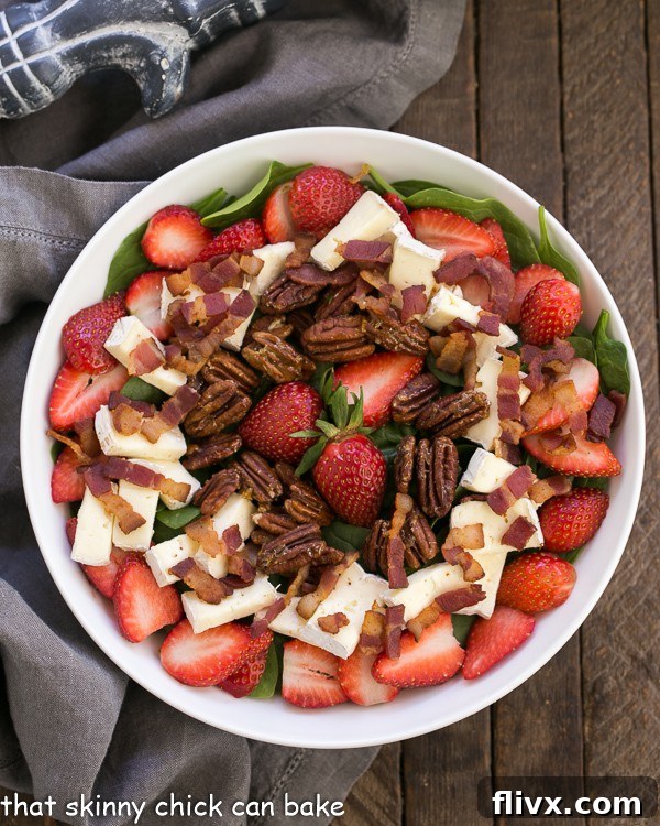An overhead view of the Strawberry Bacon Brie Salad elegantly arranged in a round white serving bowl, highlighting the colorful combination of ingredients.