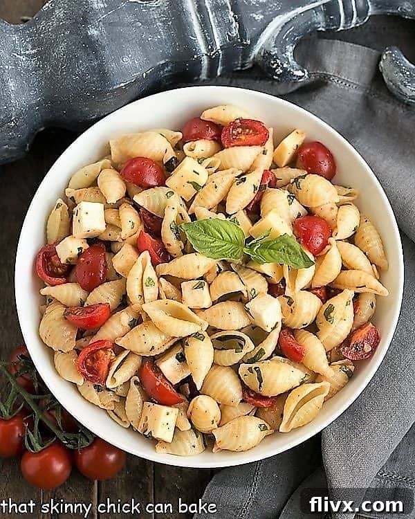 An inviting overhead view of Tomato Basil Pasta Salad with Mozzarella & Fontina nestled in a white serving bowl, showcasing its vibrant ingredients.