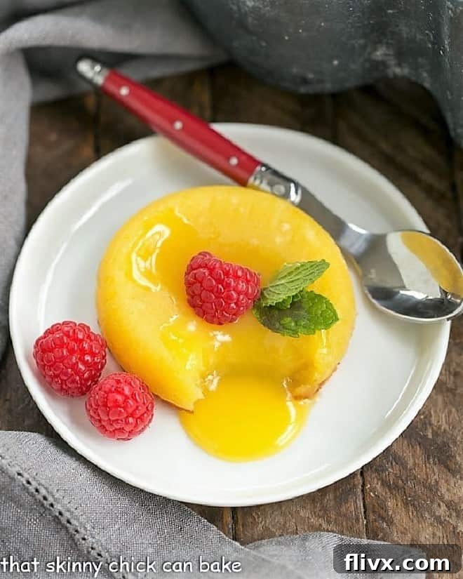 White Chocolate Molten Lava Cakes - Dreamy individual white chocolate cakes with molten centers! Decadent White Chocolate Molten Lava Cake, perfectly plated with a red-handled spoon, showcasing its rich, melting center.