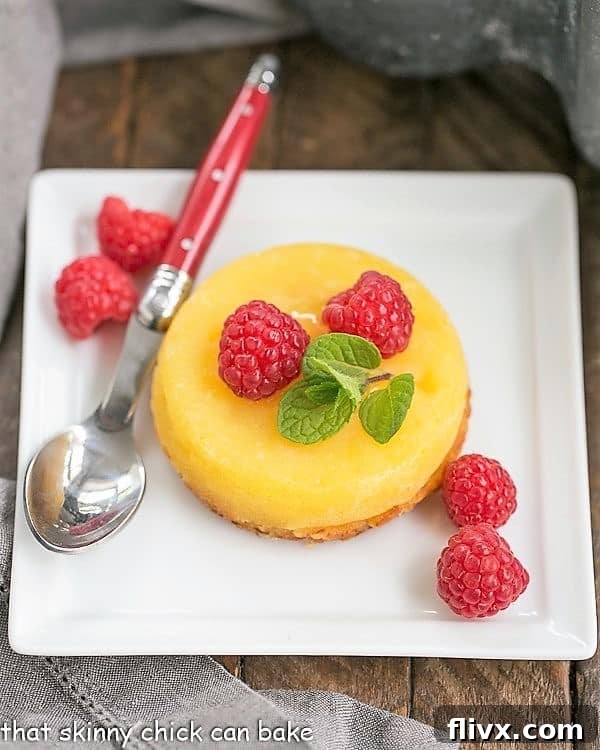 White Chocolate Molten Lava Cakes - Dreamy individual white chocolate cakes with molten centers! Exquisite White Chocolate Molten Lava Cakes, garnished with vibrant fresh raspberries, presented on a square ceramic plate.