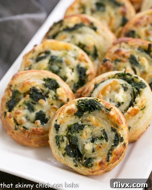 Golden brown Spinach Feta Pinwheels neatly arranged on a pristine white serving tray, ready to be enjoyed.