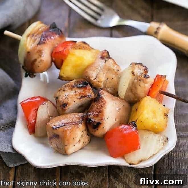 Close-up of Honey Glazed Chicken Kabobs on a small white plate, showing the succulent chicken and perfectly grilled pineapple.