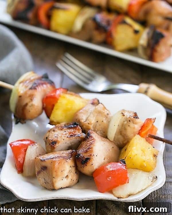 Plated Honey Glazed Chicken Kabobs on a small white plate with a full serving platter in the blurred background, creating a mouthwatering scene.