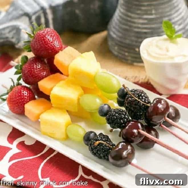 Colorful Rainbow Fruit Kabobs with a side of White Chocolate Mascarpone Dip in a small bowl.