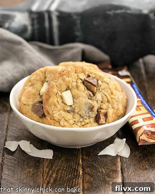 A stack of golden-brown Chewy Oatmeal Toffee Cookies, showing visible chunks of toffee and white chocolate.