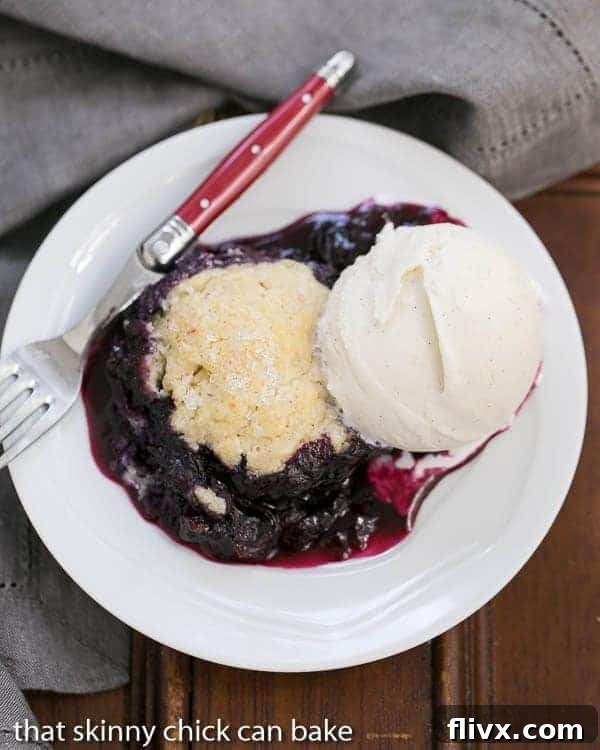 Grilled Blueberry Cobbler with a biscuit topping, bubbling in a cast iron pan.