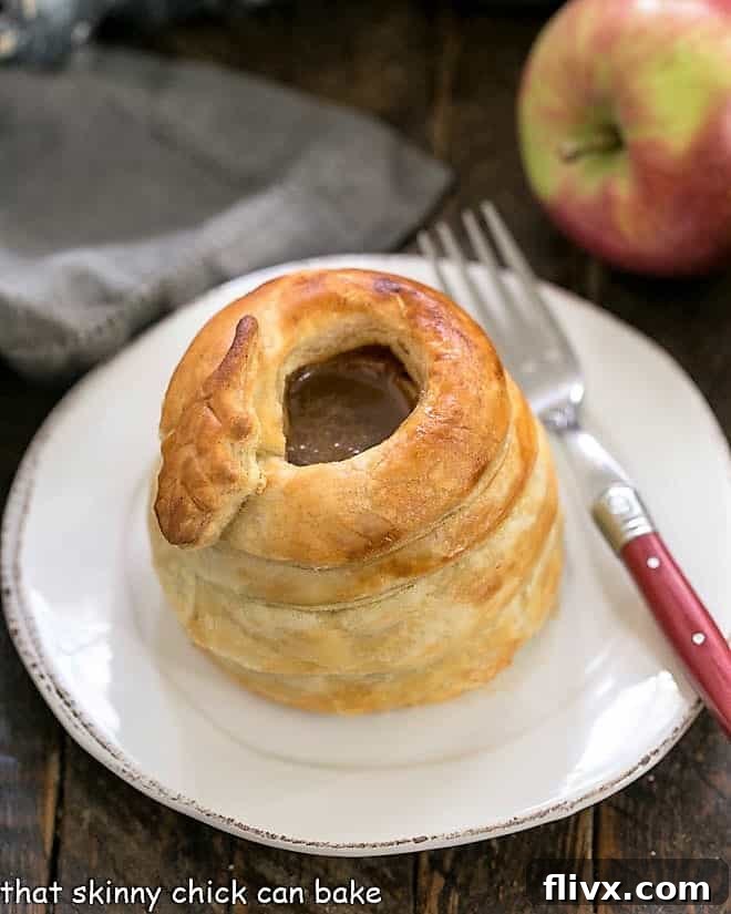 A single elegantly wrapped pastry caramel apple on a simple round white plate, ready to be served.