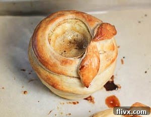 Several beautiful Pastry Wrapped Caramel Apples arranged on a parchment-lined baking sheet, freshly baked.