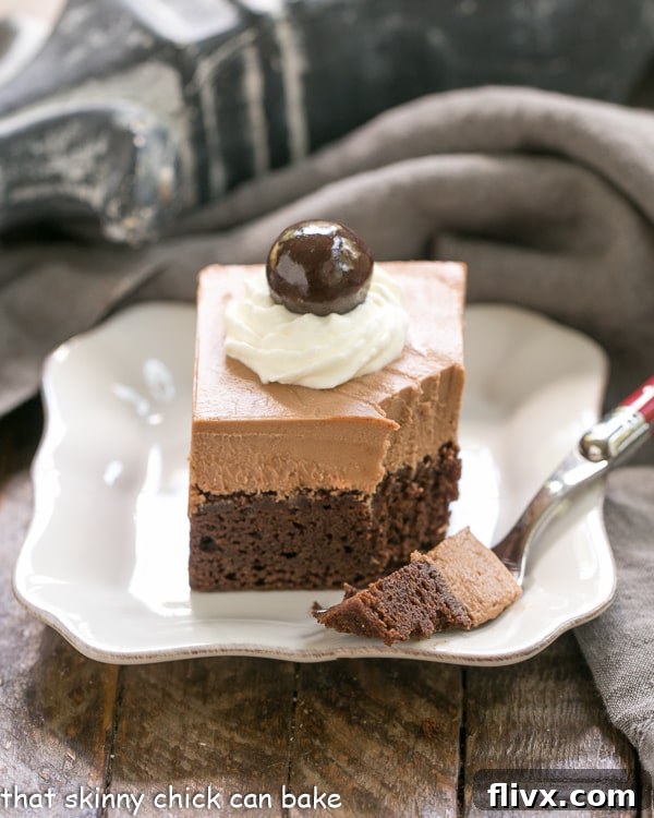A French Silk Pie Brownie with a portion removed by a fork, showcasing its luscious layers, resting on a clean white square plate.