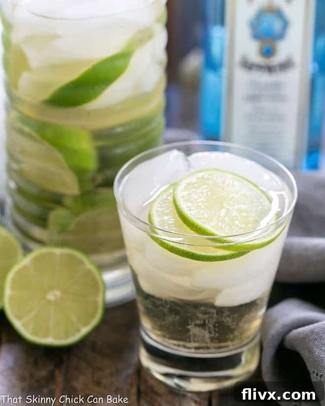 A refreshing St. Germain Gin and Tonic Cocktail in a short glass, filled with ice and garnished with bright lime slices.