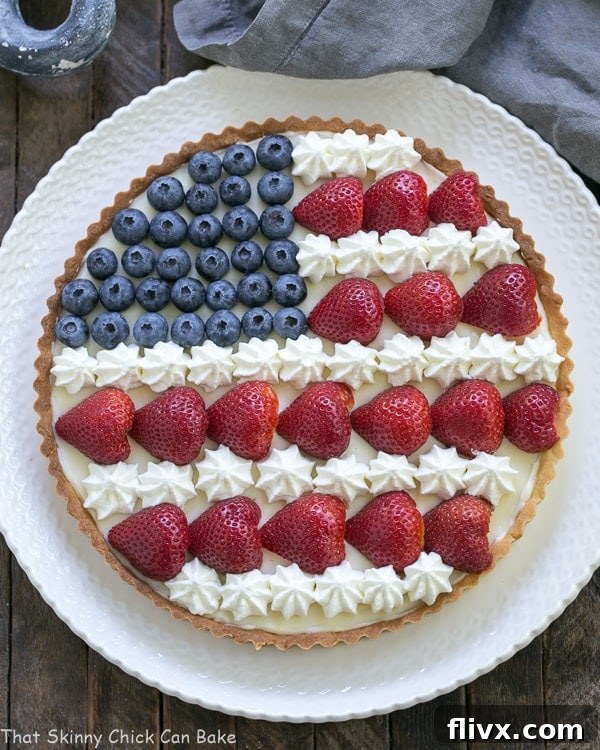Overhead view of an American Flag Fruit Tart on white serving plate.
