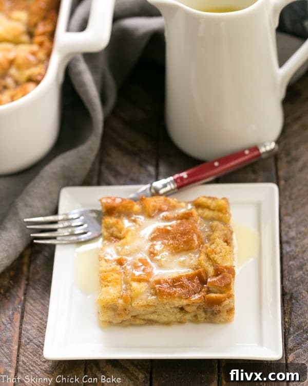 Slice of Cinnamon Bread Pudding with Whiskey Sauce on a square white plate with a red handled fork.