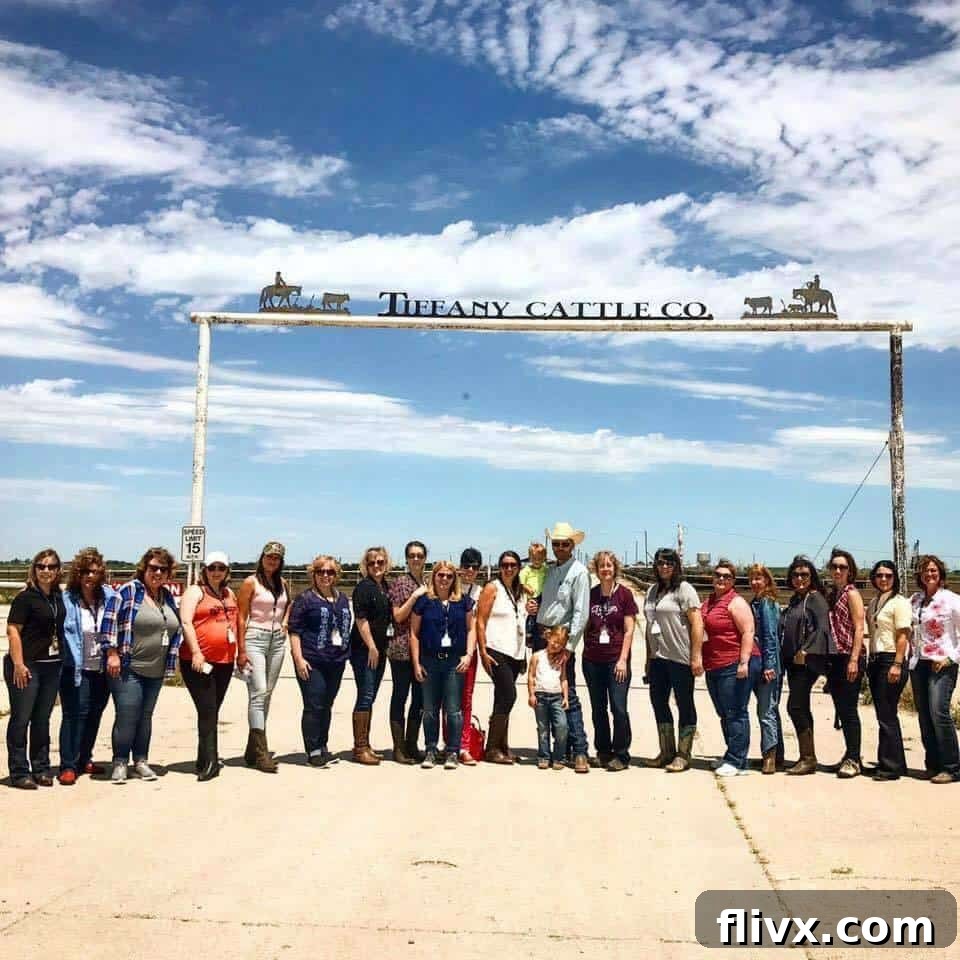 A group of people standing in front of the sign to a cattle ranch.