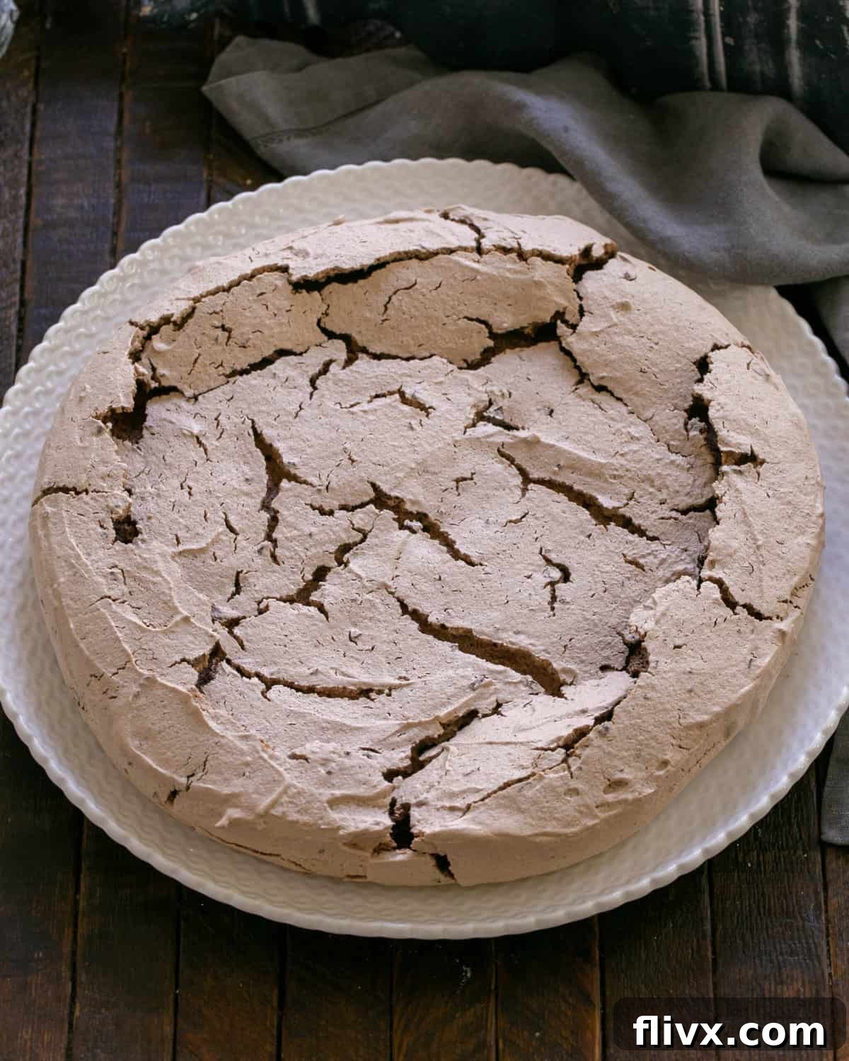 Chocolate pavlova baking in the oven, showing its characteristic cracked surface.