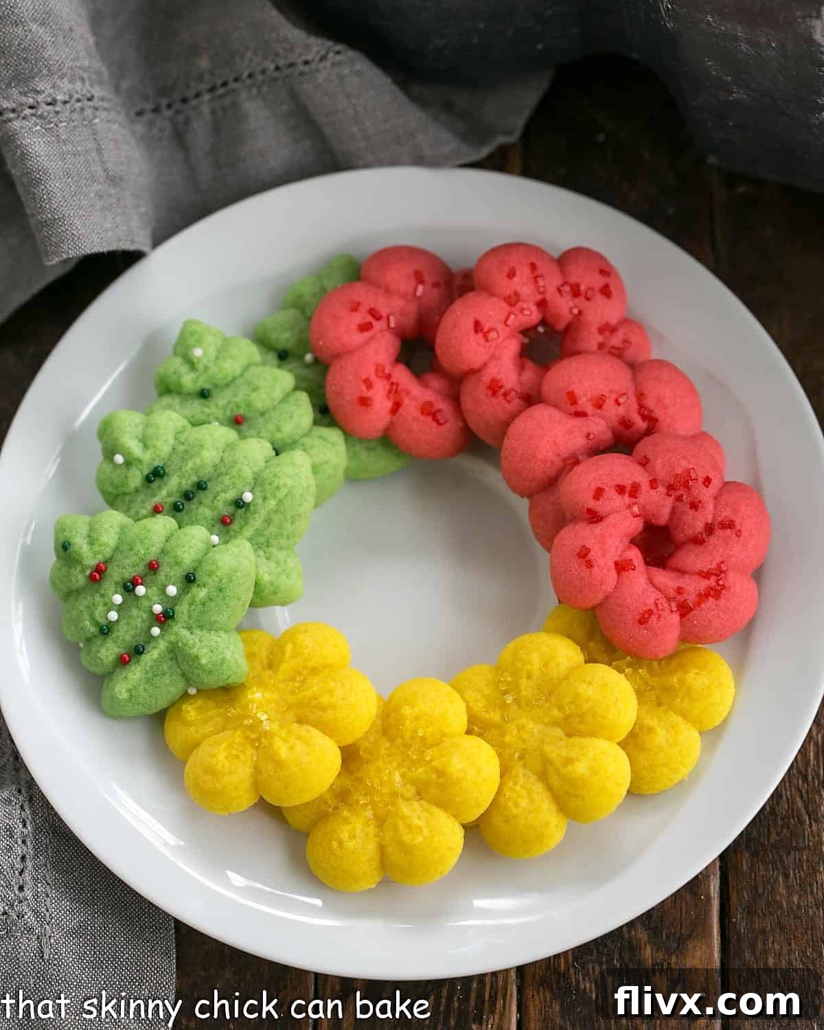 Overhead view of decorated spritz cookies on a round white plate.