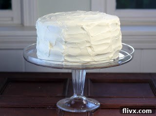 A red velvet cake on a glass stand in front of a window