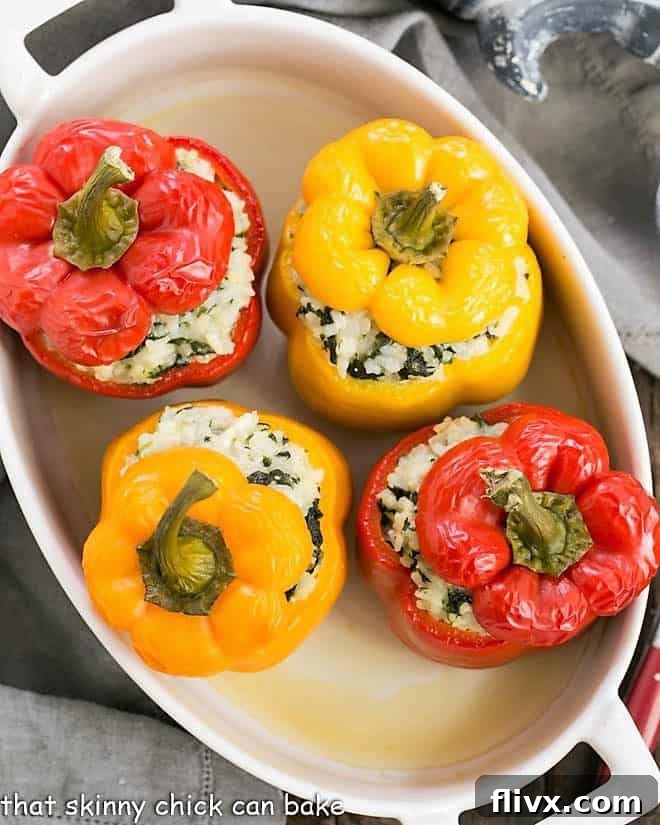 Four golden-brown rice packed peppers baked in a white casserole dish