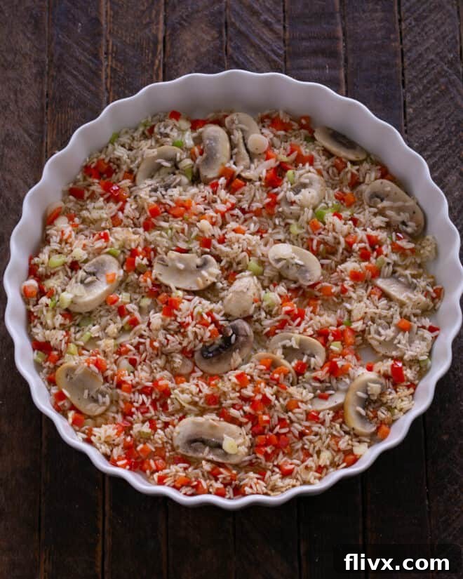 Sautéed rice mixture being transferred into a greased baking dish.