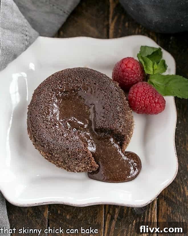 A perfectly baked molten lava cake with a forkful revealing its rich, warm, fudgy chocolate interior on a pristine white plate, ready to be devoured.