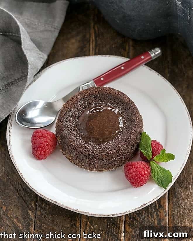 An enticing overhead view of a luscious molten lava cake, artfully garnished with vibrant red raspberries, beautifully showcasing its rich chocolate exterior and the promise of a perfectly gooey, warm center.