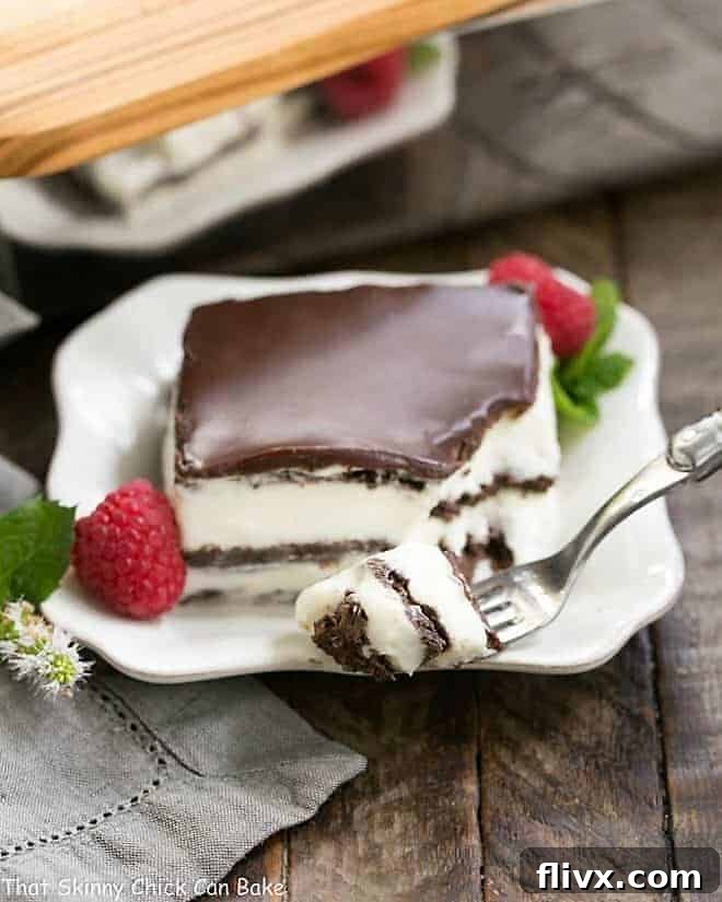 A piece of no bake chocolate lasagna on a plate with a fork with a bite on the tines, garnished with a fresh raspberry and mint.
