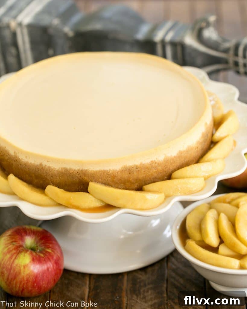 A stunning Easy Sour Cream Cheesecake with Caramel Apples presented on an elegant white ceramic cake stand, ready to be served.