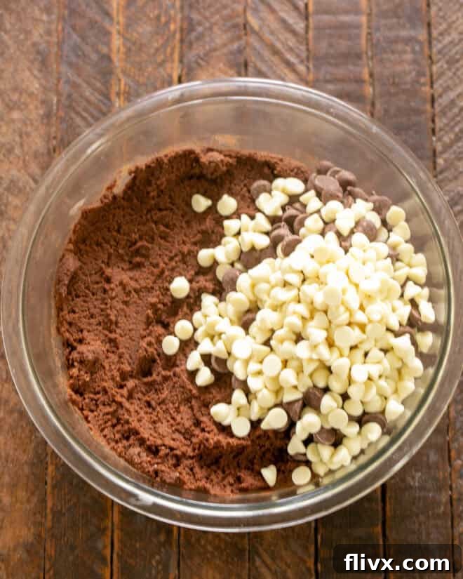 Milk and white chocolate chips being added to the cookie dough.