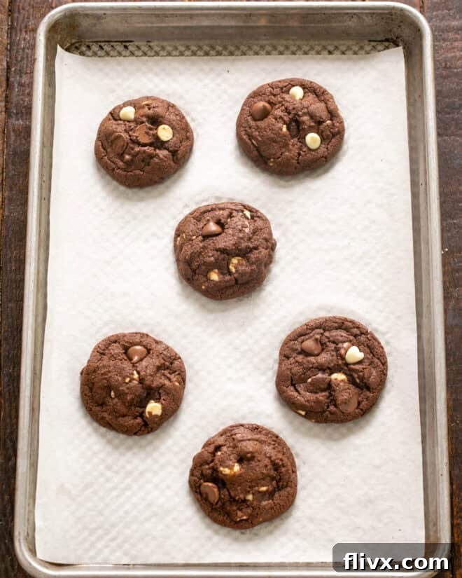 Freshly baked Triple Chocolate Fudge Cookies on a baking sheet, just out of the oven.