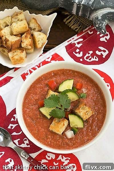 Overhead view of Classic Gazpacho with Homemade Croutons in a white bowl topped with cucumbers, peppers and croutons.