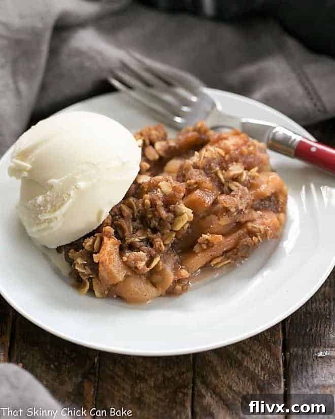 Easy Slow Cooker Apple Crisp with Oatmeal served on a white dessert plate with a scoop of melting vanilla ice cream.