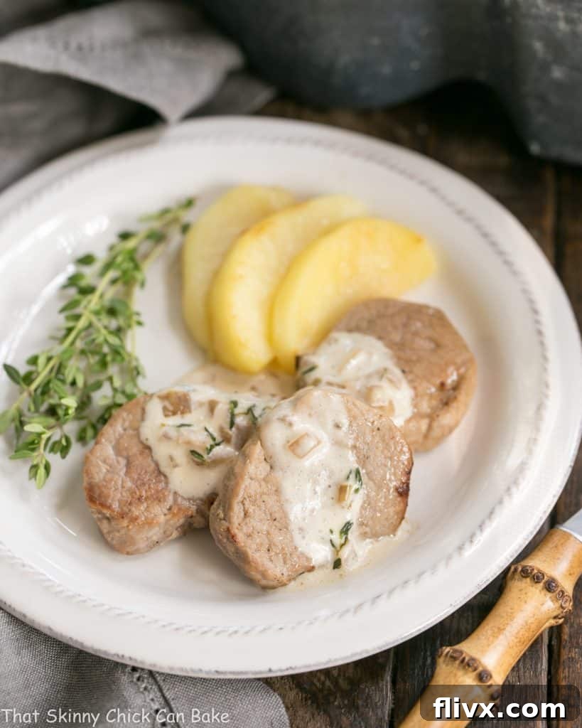 Close up of Apple Topped Pork Medallions with Calvados Cream Sauce and a sprinkle of fresh thyme leaves.
