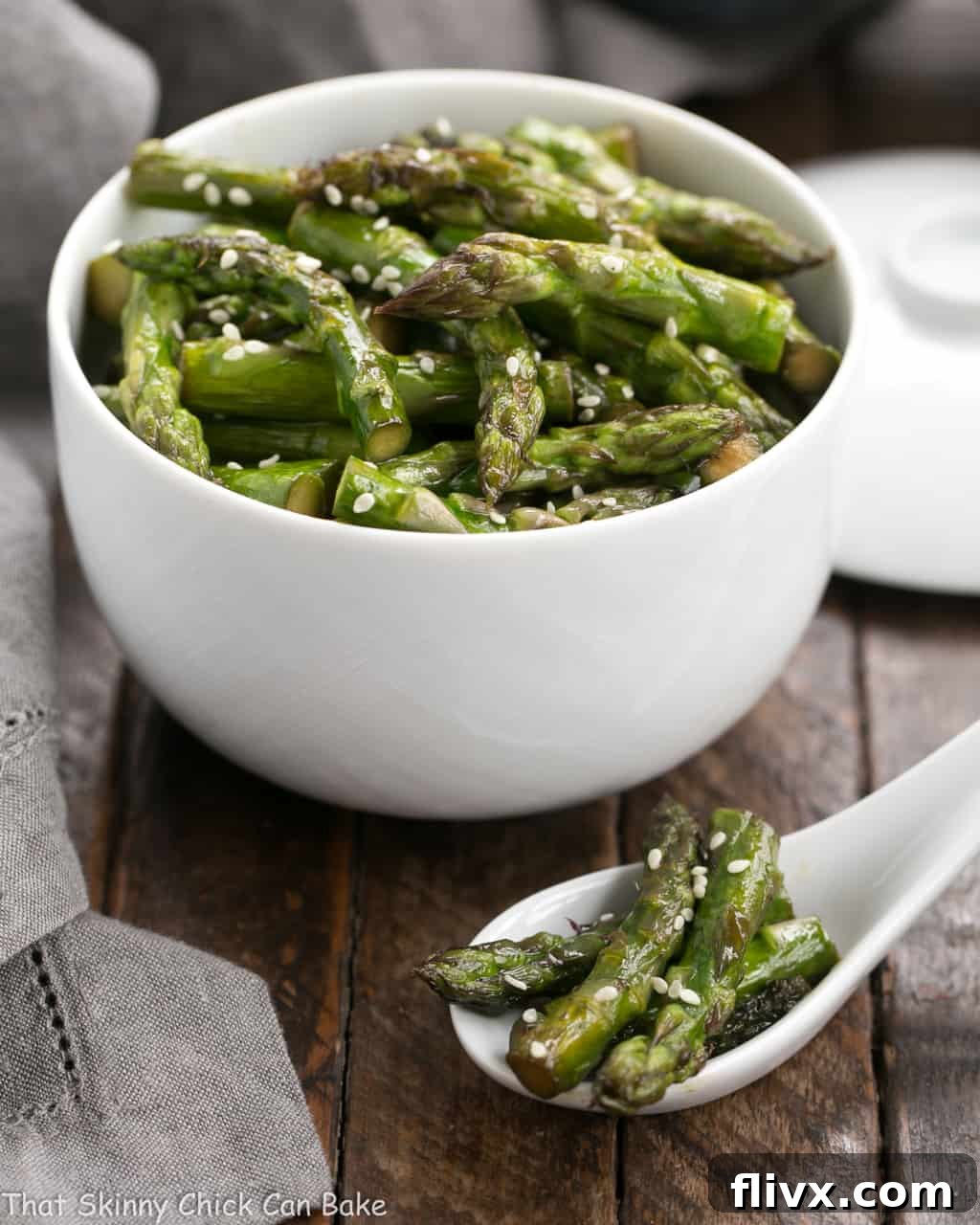 Stir fried asparagus in a white bowl and in a white Chinese soup spoon.